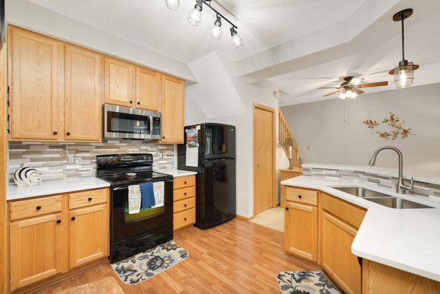 kitchen with a sink, black appliances, light countertops, light wood-style floors, and backsplash