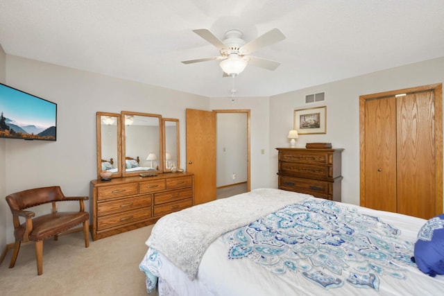 bedroom with a closet, visible vents, light carpet, and ceiling fan