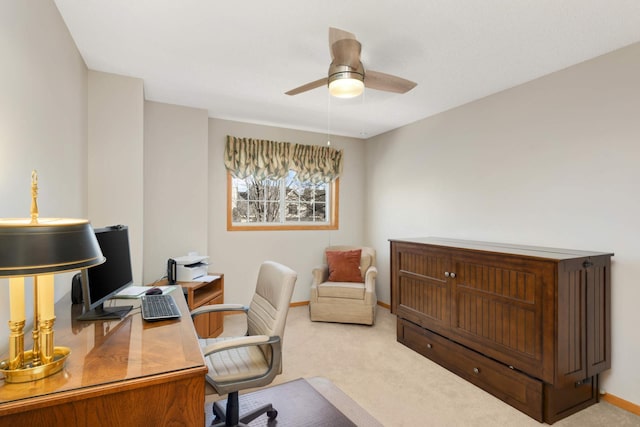 carpeted office space featuring baseboards and ceiling fan