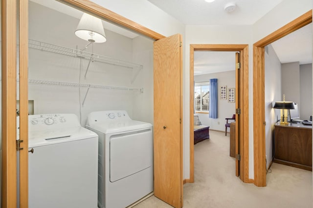 laundry area with washer and dryer, baseboards, light carpet, and laundry area