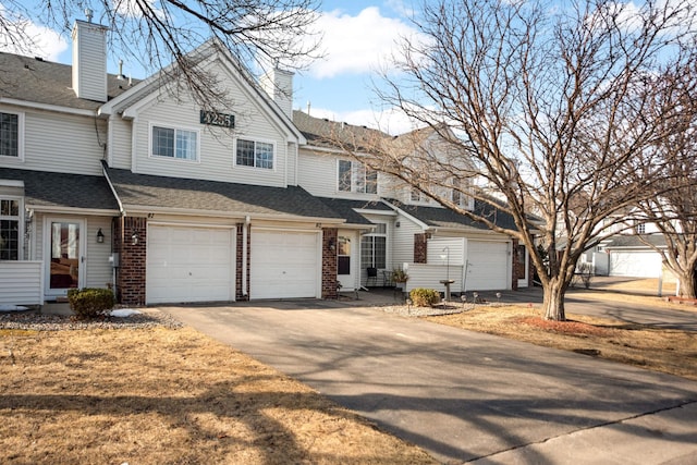 view of front of property with driveway, roof with shingles, a chimney, a garage, and brick siding