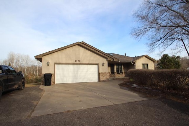 ranch-style home featuring a garage, concrete driveway, and stucco siding