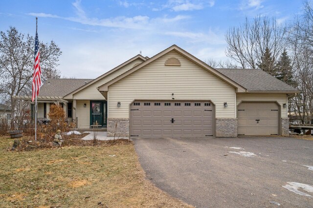 view of front of house featuring aphalt driveway, an attached garage, brick siding, and a shingled roof