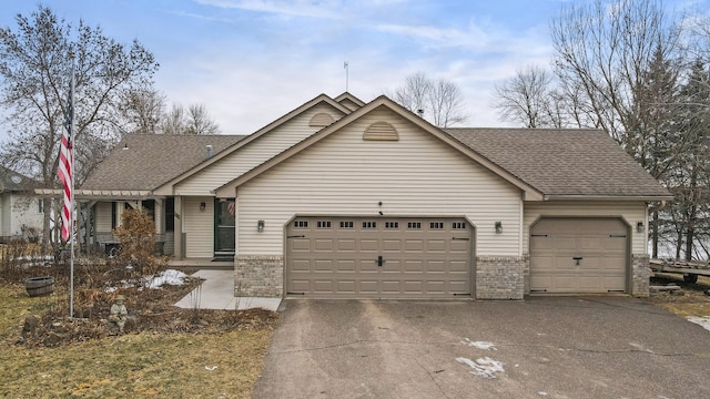 view of front facade with brick siding, driveway, a garage, and roof with shingles