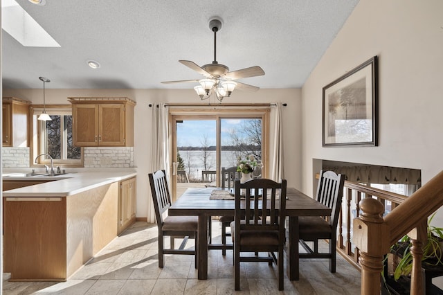 dining room with a textured ceiling, a healthy amount of sunlight, ceiling fan, and vaulted ceiling