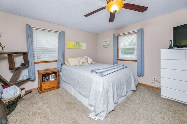 bedroom with ceiling fan, carpet flooring, baseboards, and a textured ceiling