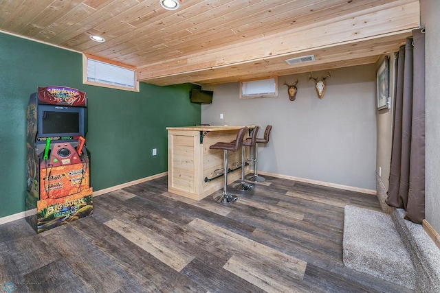 interior space featuring baseboards, visible vents, dark wood finished floors, a bar, and wooden ceiling