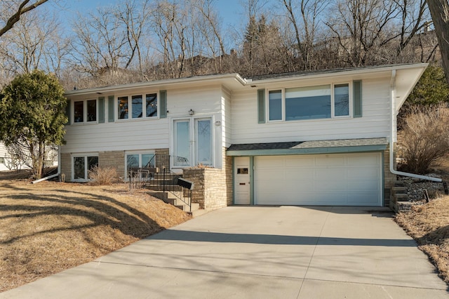 bi-level home featuring stone siding, driveway, and a garage