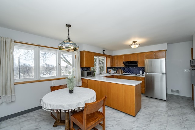 kitchen featuring visible vents, brown cabinets, range hood, a peninsula, and appliances with stainless steel finishes