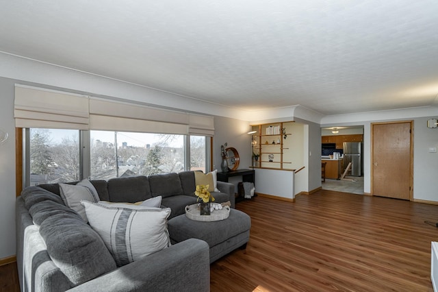 living room featuring a textured ceiling, baseboards, and wood finished floors