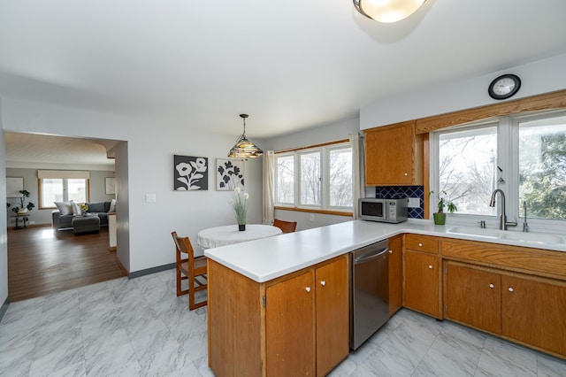 kitchen featuring a peninsula, a sink, stainless steel appliances, light countertops, and marble finish floor