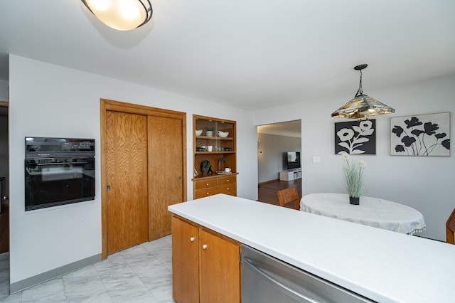 kitchen featuring brown cabinets, pendant lighting, marble finish floor, black oven, and light countertops