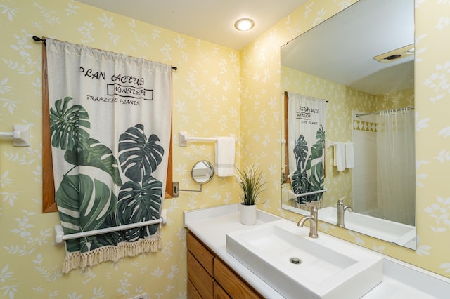 bathroom with wallpapered walls, a shower with curtain, and vanity