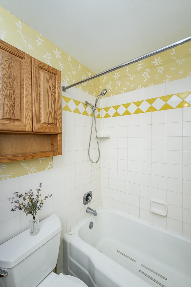 full bath featuring wallpapered walls, toilet, and washtub / shower combination