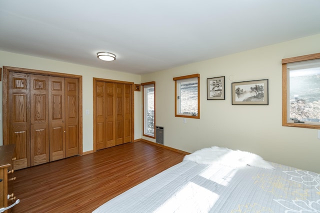 bedroom featuring baseboards, multiple closets, and wood finished floors