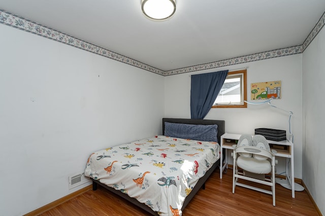 bedroom with wood finished floors, visible vents, and baseboards