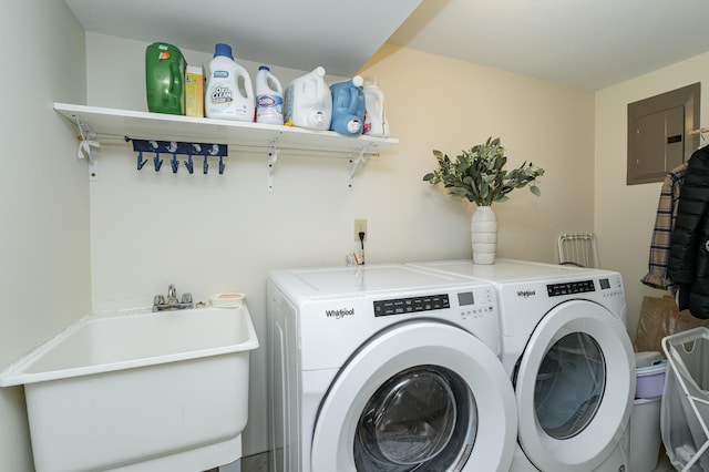 washroom with electric panel, laundry area, washer and dryer, and a sink