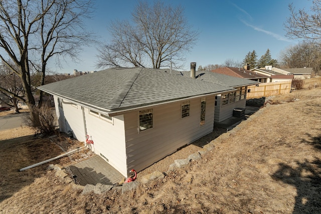 view of side of property with fence and a shingled roof