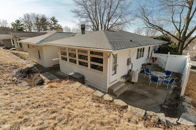 rear view of property with a gate, fence, roof with shingles, and a patio area