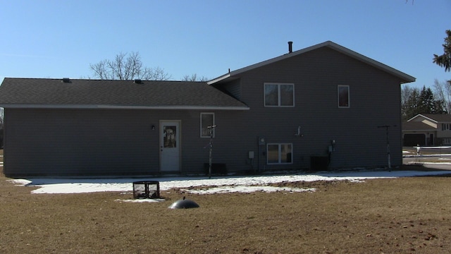 rear view of property featuring a lawn and a shingled roof