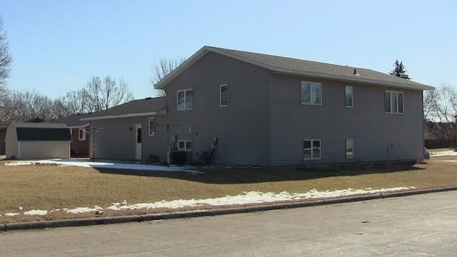 view of side of property with an outbuilding, a lawn, and a shed