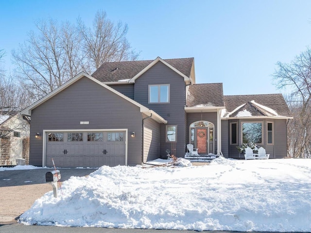 traditional home with an attached garage and a shingled roof