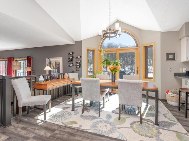 dining room featuring a wealth of natural light, lofted ceiling, a notable chandelier, and wood finished floors