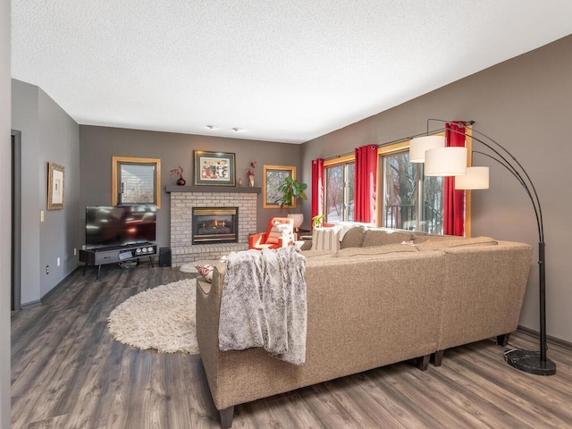 living area with wood finished floors, a fireplace, baseboards, and a textured ceiling