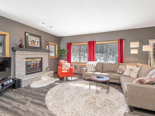 living room with a brick fireplace, wood finished floors, and a textured ceiling