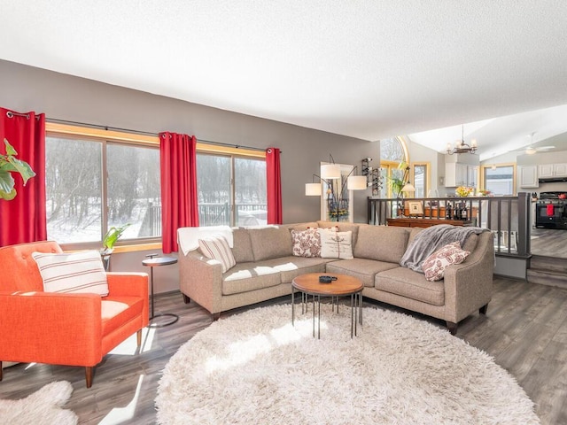 living area featuring a chandelier, a textured ceiling, lofted ceiling, and wood finished floors