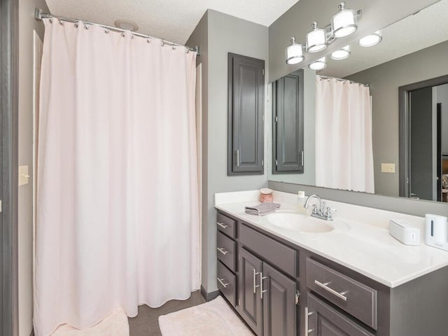 full bathroom featuring a textured ceiling and vanity