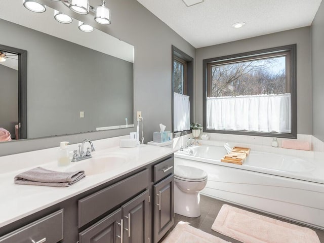 full bath featuring tile patterned flooring, toilet, vanity, a bath, and a textured ceiling