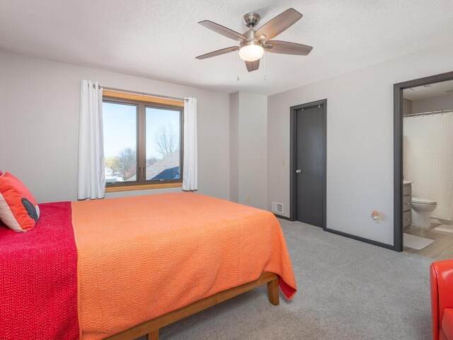 bedroom with ensuite bath, visible vents, a textured ceiling, and carpet