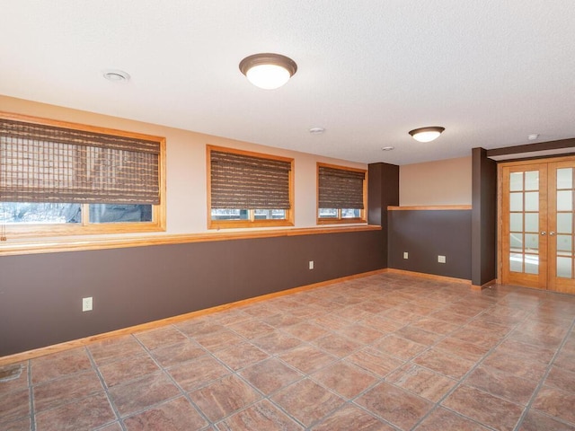 unfurnished room with french doors, baseboards, and a textured ceiling