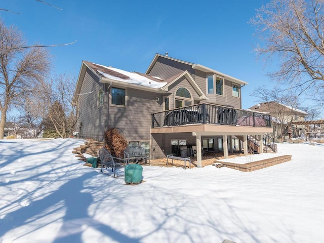 snow covered house featuring a wooden deck and stairs