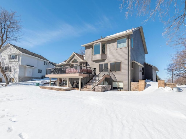 snow covered back of property featuring stairway and a deck