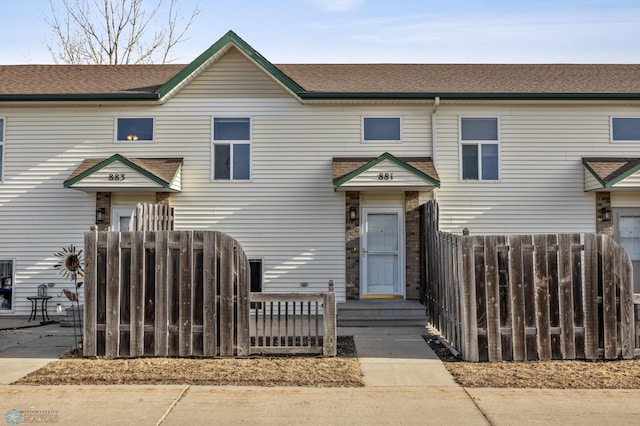 view of property with roof with shingles and fence