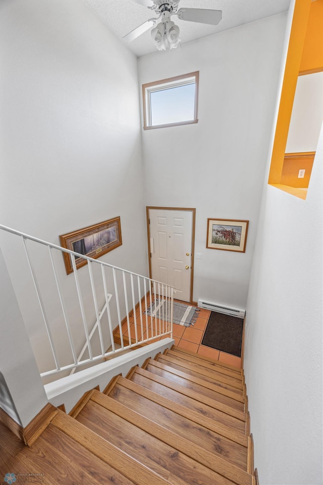 stairs featuring a ceiling fan and a baseboard radiator