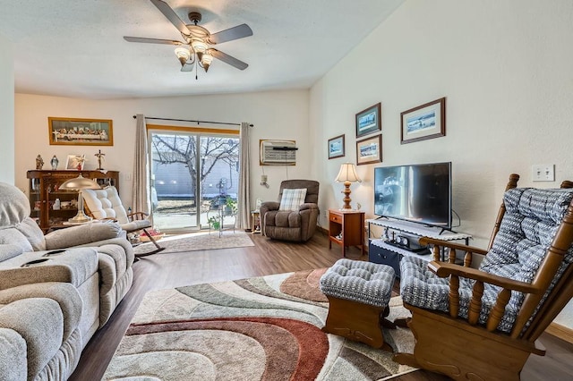living area featuring a ceiling fan, an AC wall unit, and wood finished floors