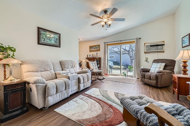 living room with a ceiling fan, vaulted ceiling, wood finished floors, and a wall mounted air conditioner