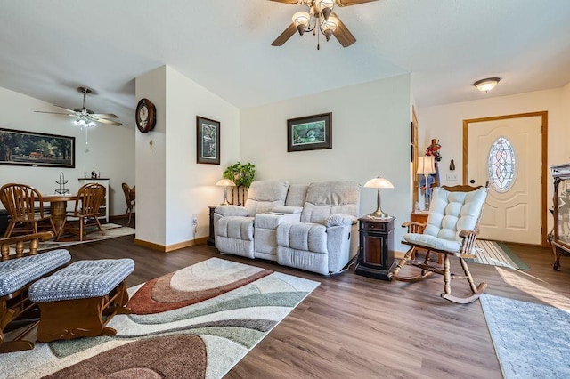 living room featuring ceiling fan, baseboards, wood finished floors, and vaulted ceiling