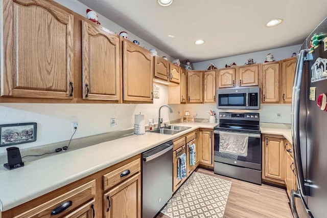 kitchen with recessed lighting, a sink, light countertops, light wood-style floors, and appliances with stainless steel finishes