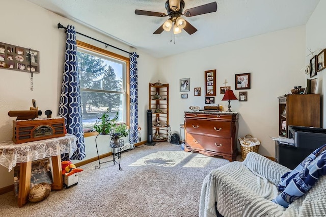 living area featuring baseboards, a ceiling fan, and carpet flooring