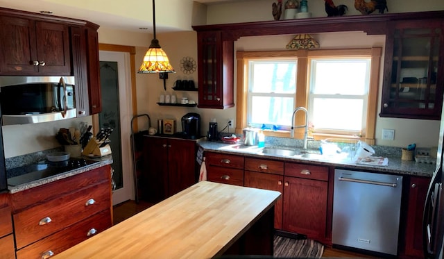 kitchen with pendant lighting, butcher block counters, stainless steel appliances, and a sink