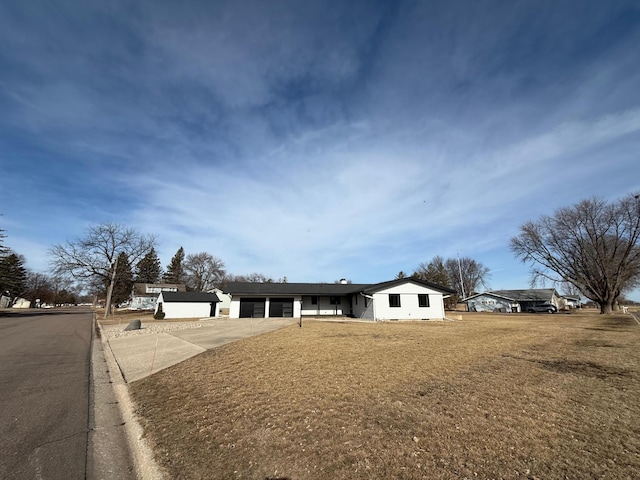 single story home featuring a front lawn, an attached garage, and driveway