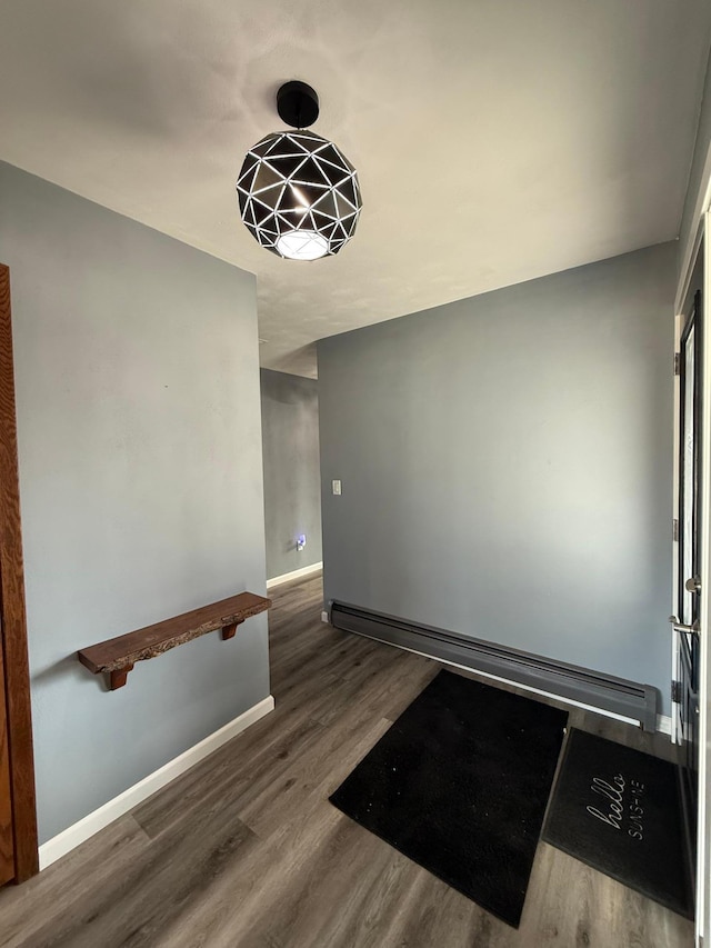 interior space featuring a baseboard heating unit, baseboards, and wood finished floors