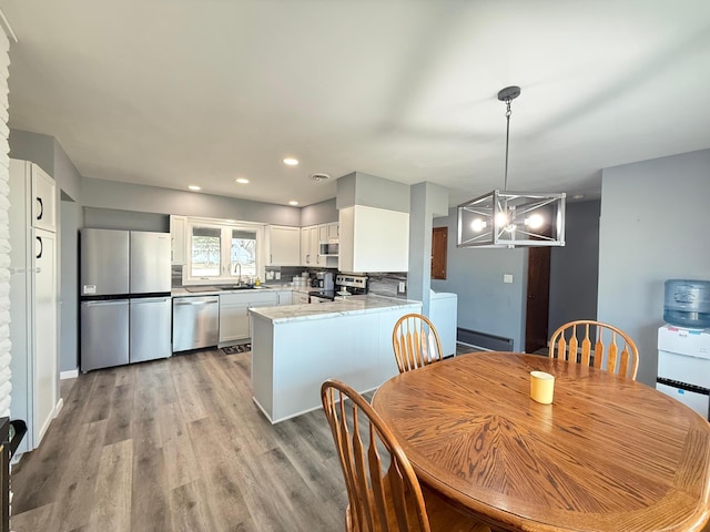 dining area with a chandelier, recessed lighting, and light wood-type flooring