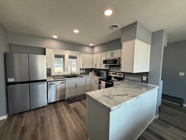 kitchen with visible vents, baseboard heating, stainless steel appliances, white cabinetry, and a sink