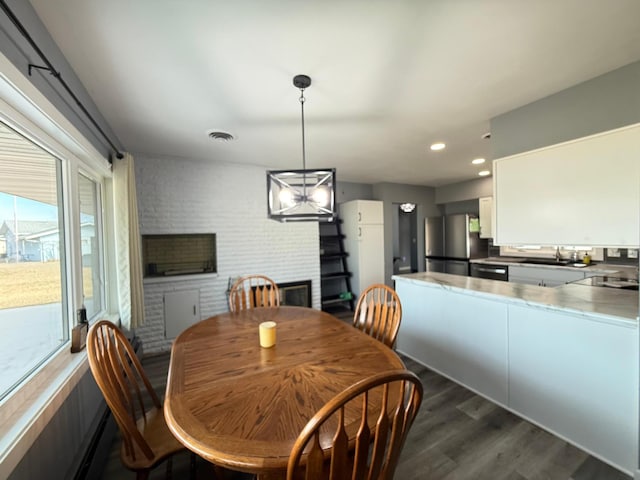 dining area with recessed lighting, dark wood-style floors, visible vents, and brick wall