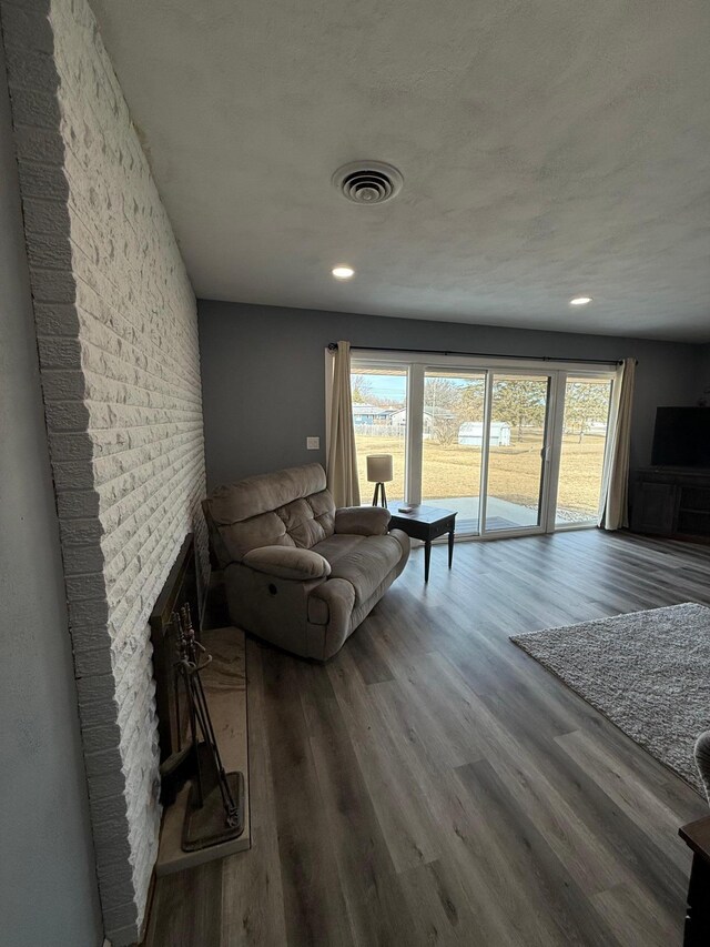 living room with recessed lighting, visible vents, wood finished floors, and a fireplace